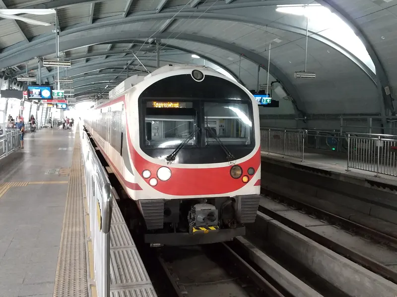A red and white Airport Rail Link train standing at an elevated platform at Phaya Thai station.